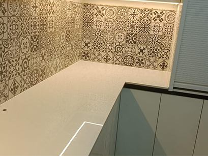 A modern kitchen in Bangalore featuring a white countertop, green cabinets, and a unique patterned backsplash, blending functionality with vibrant design elements.